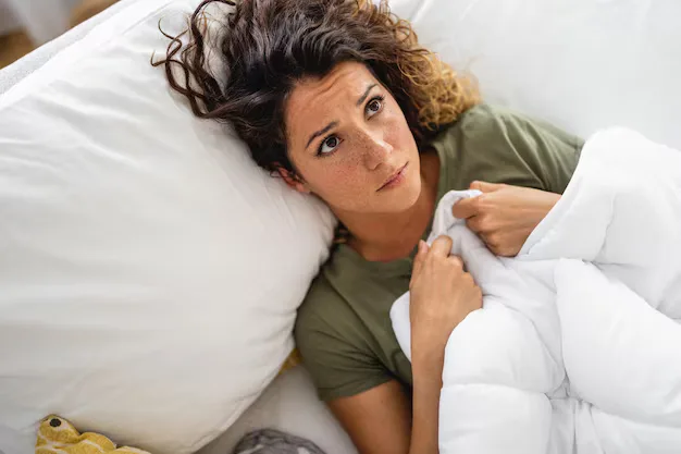 Mulher deitada na cama, pensativa